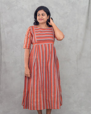 Woman wearing a striped feeding dress against a plain background