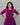 Woman wearing a purple maternity dress with pink accents against a gray background