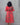 Person wearing a red and green patterned dress against a gray background